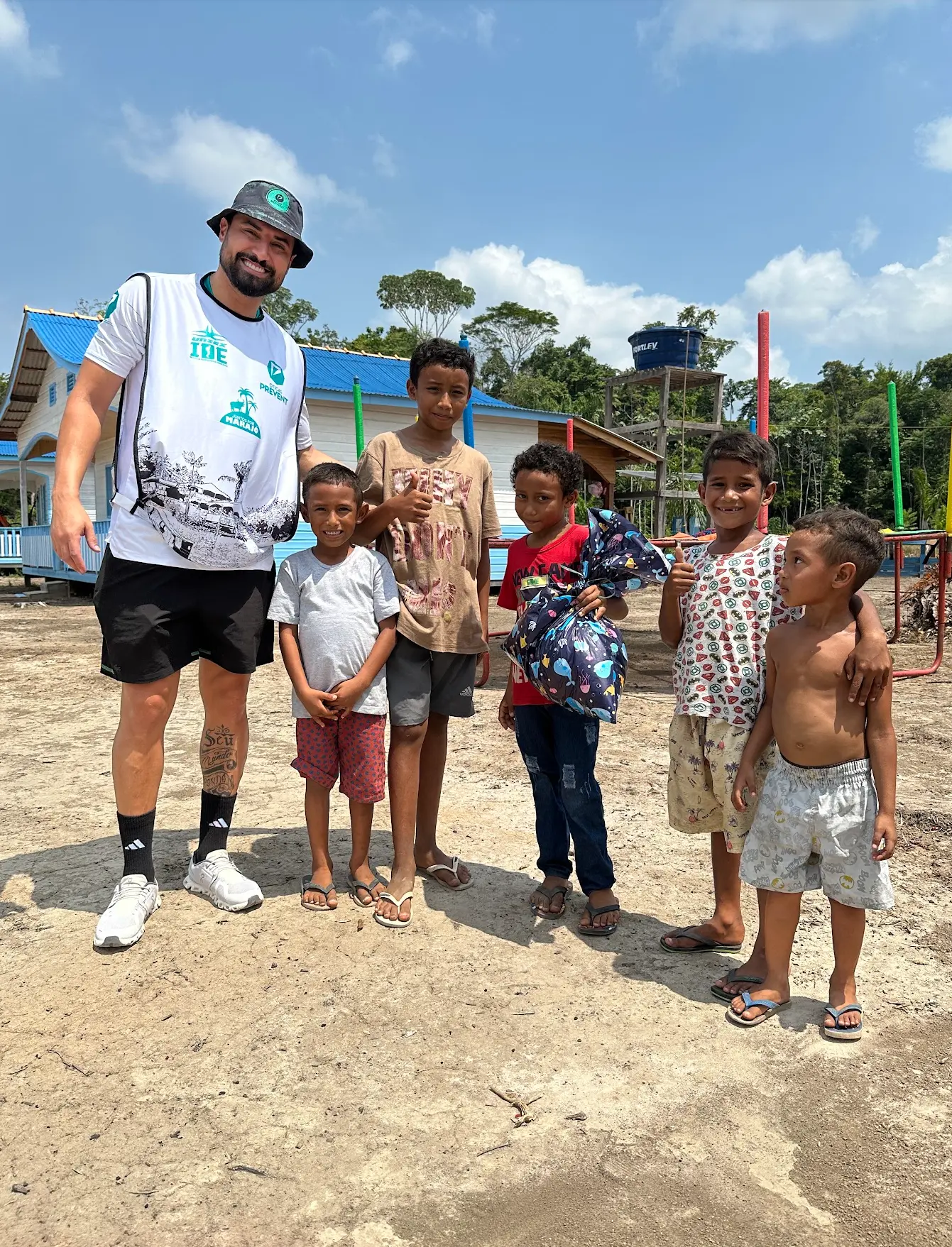 Voluntário de chapéu preto com cinco meninos locais em caminho de terra no Marajó